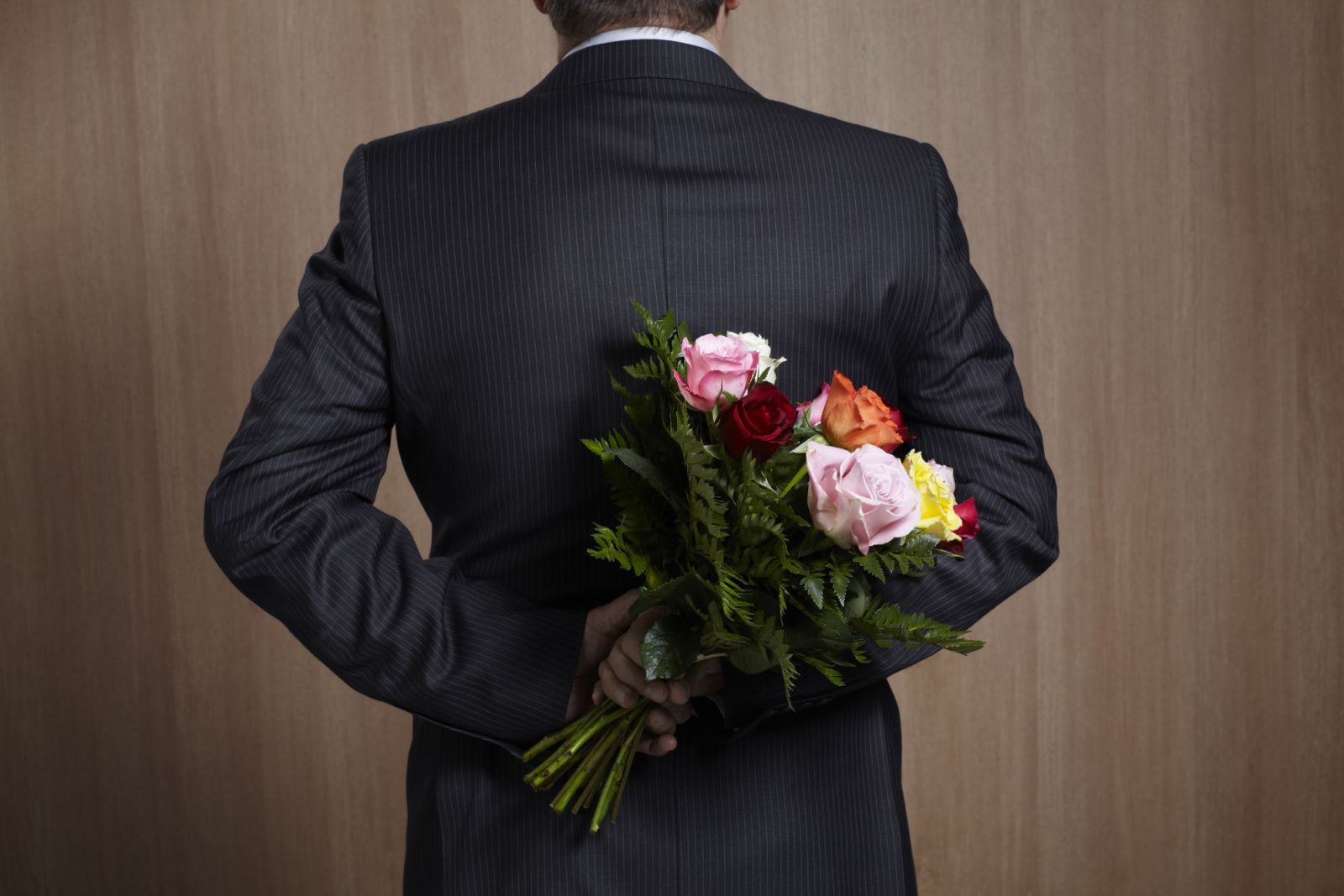 man in suit holding a bouquet of flowers in the back