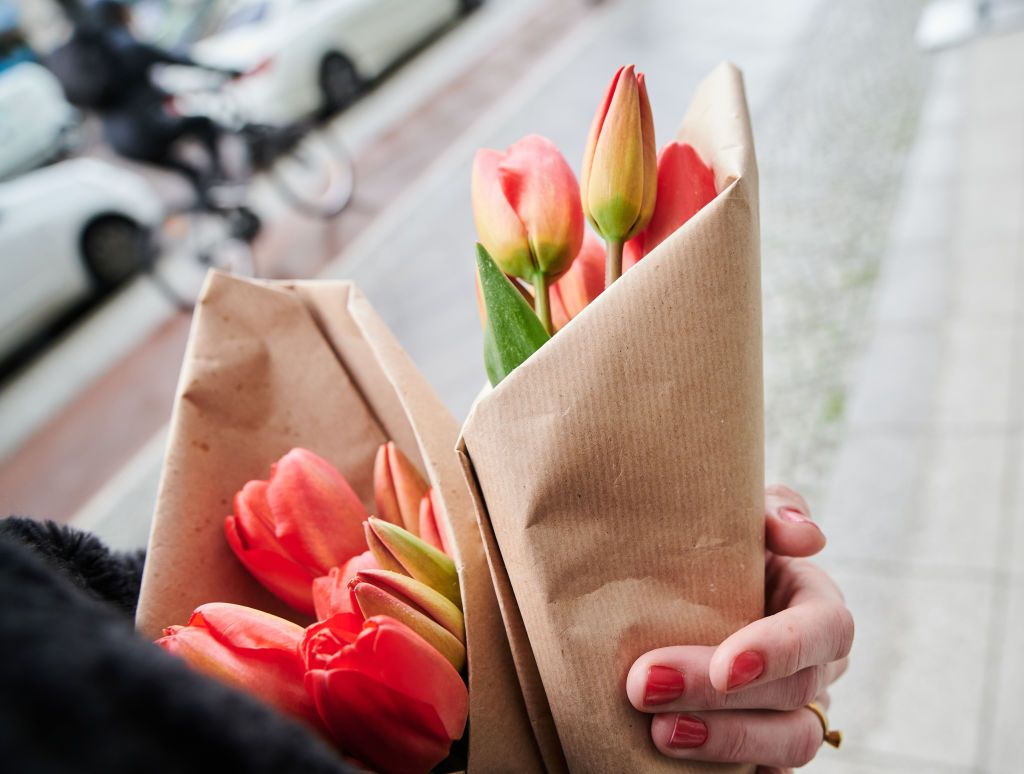 ILLUSTRATION - 04 May 2021, Berlin: A woman holds tulips wrapped in paper and walks down the street. Photo: Annette Riedl/dpa (Photo by Annette Riedl/picture alliance via Getty Images)