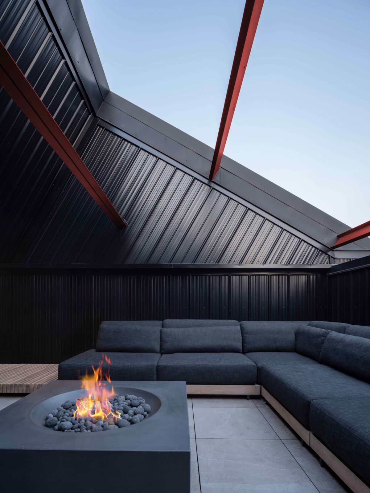 The rooftop terrace with black metal siding and a fireplace coffee table