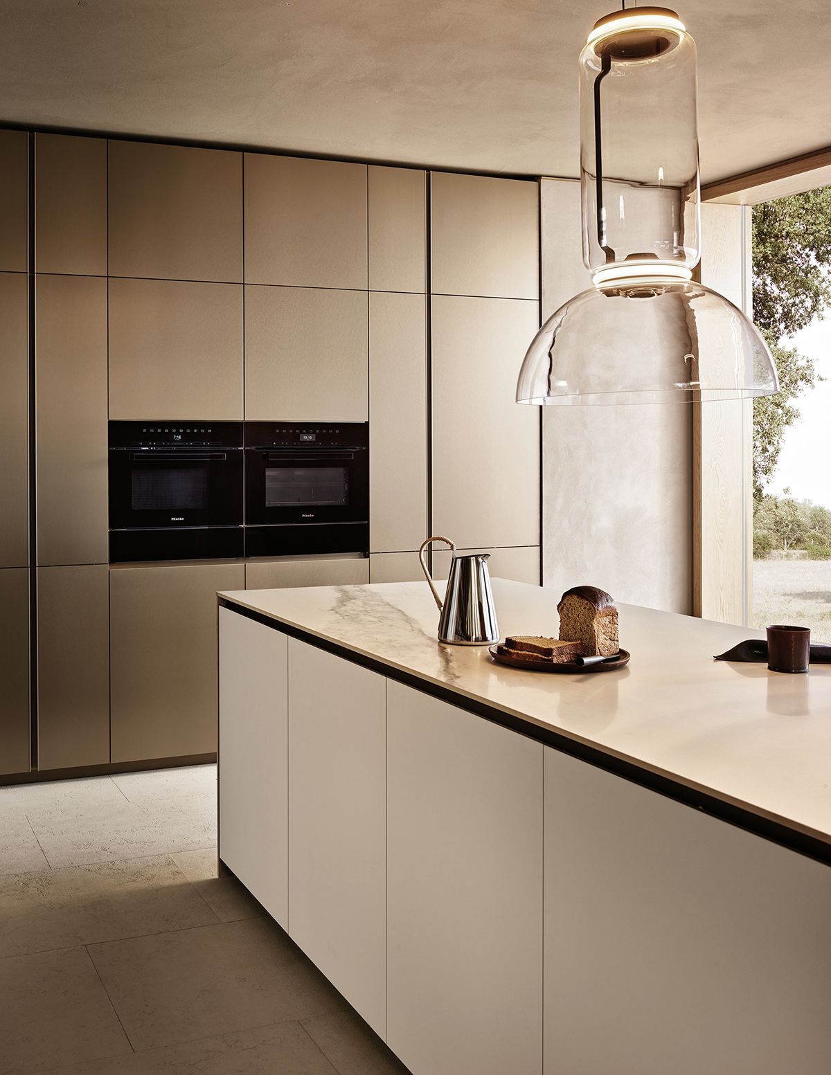 The Poliform Alea Pro kitchen system presents a clean-cut aesthetic that is perfect for contrasting with both rugged and delicate elements, such as the glass lamp above the kitchen island