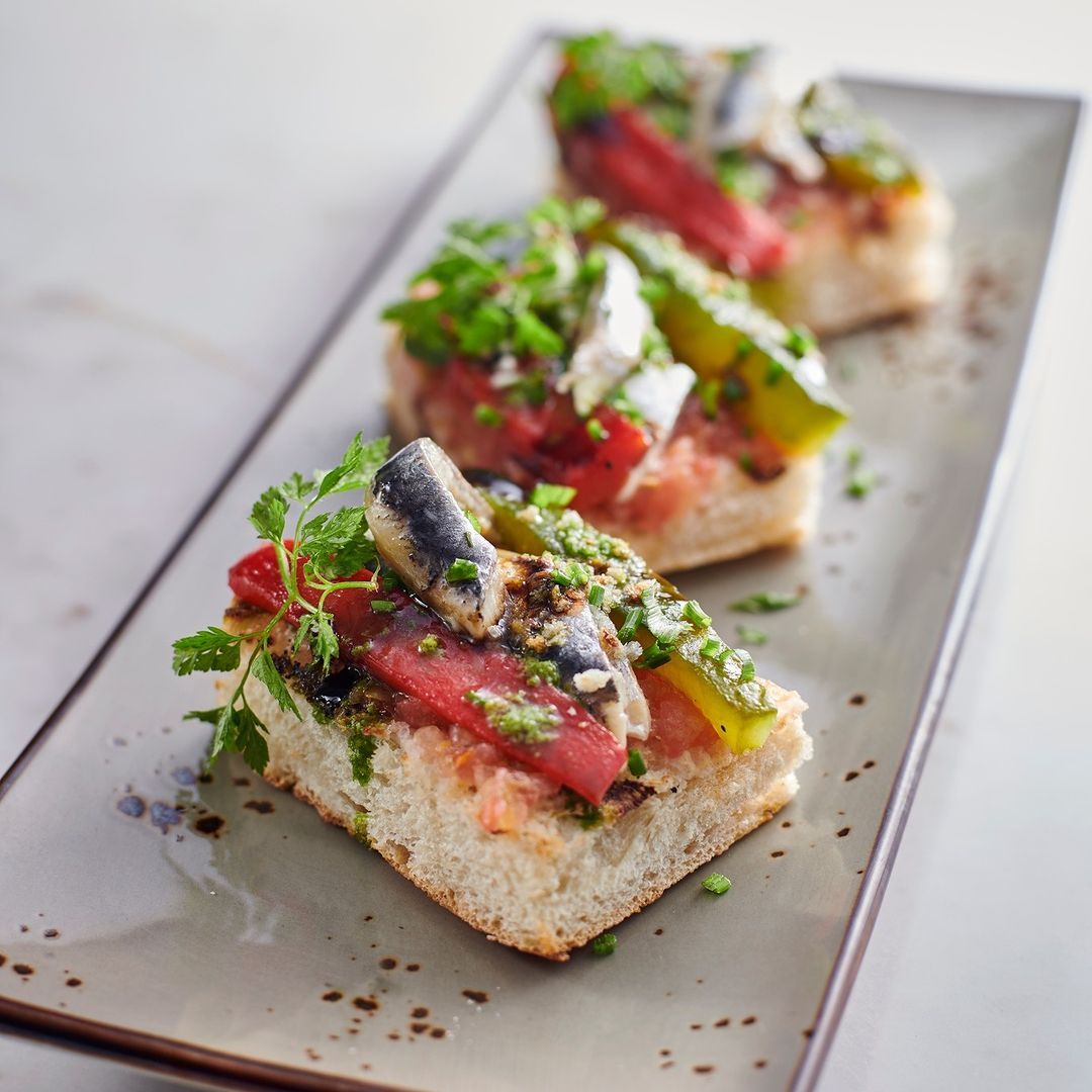 White and black anchovies with tomatoes on a sliced baguette (Photo: Instagram / @lasmeninastrx)