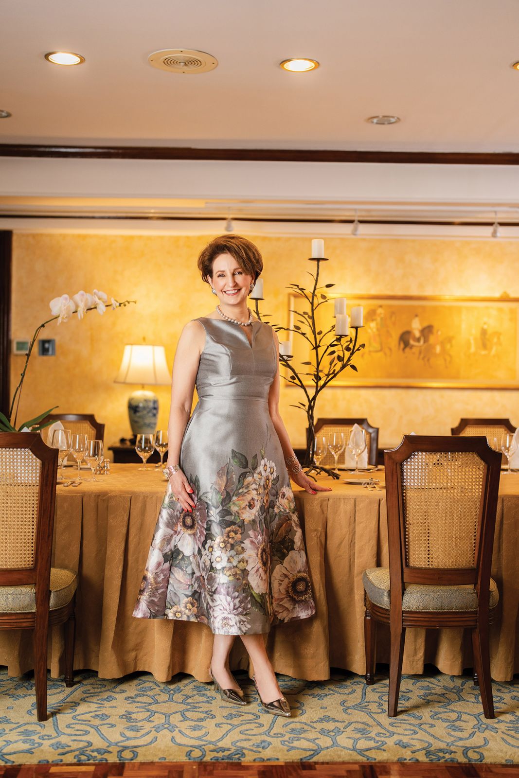 Ambassador MaryKay Carlson at the dining room, in a Kay Unger dress, Sam Edelman shoes, grey pearl earrings and necklace
