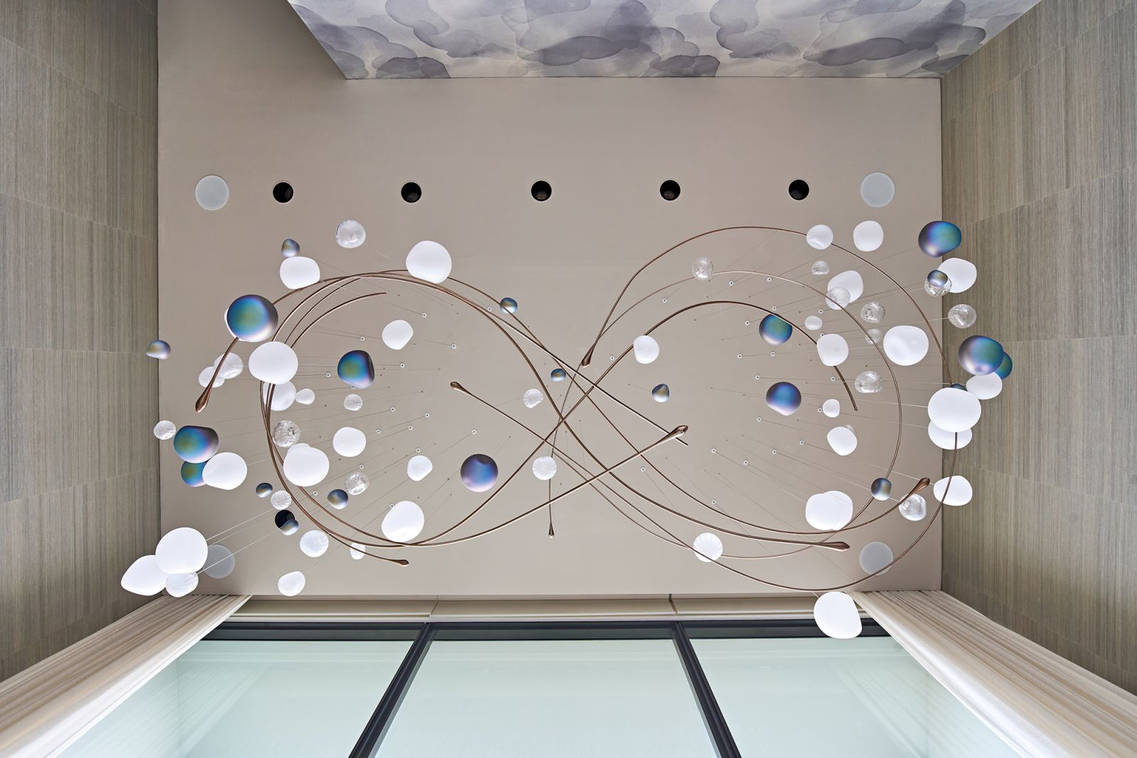 The chandelier takes on the form of an infinity symbol surrounded by celestial bodies when viewed from below