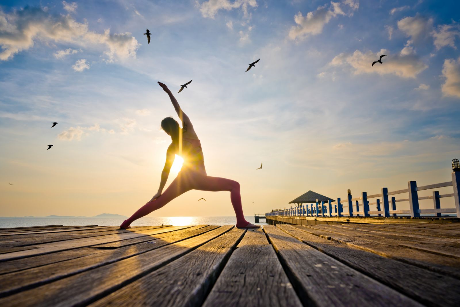 Women in action of yoga practice exercise training in seaside of the bridge pier at light sunset, cheerfully enjoy and happiness of life balance exercise