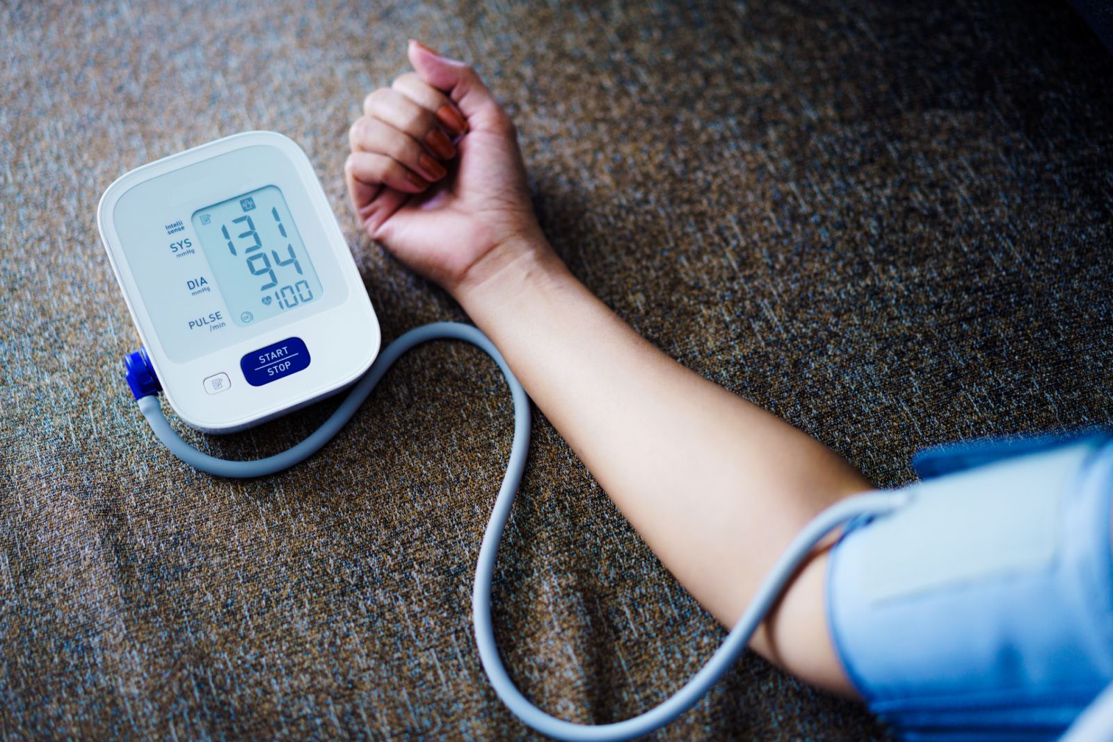 Asian Woman self blood pressure and heart rate measurement on blood pressure monitor recording the data at home