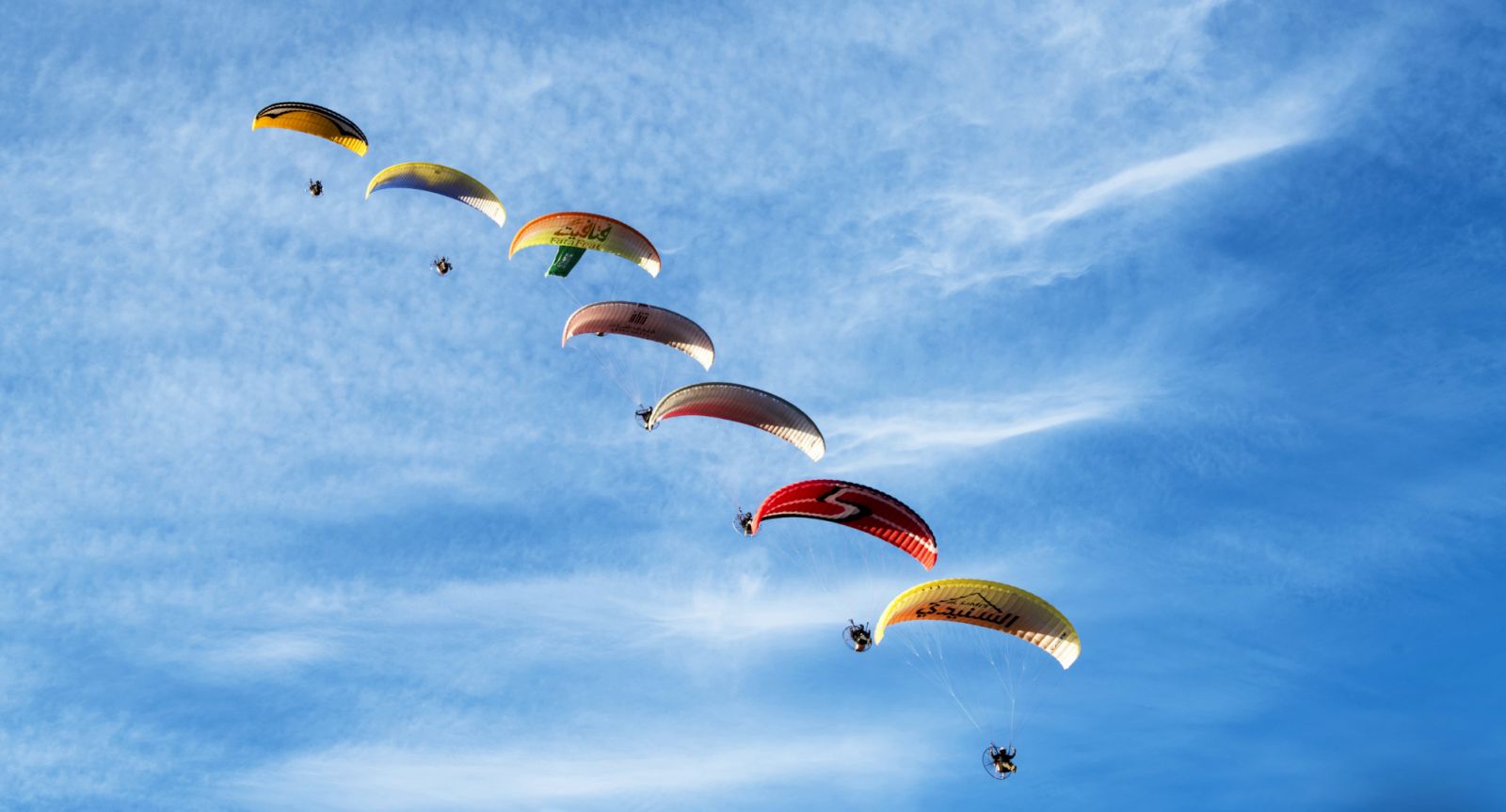 A group of paragliders descending towards the ground