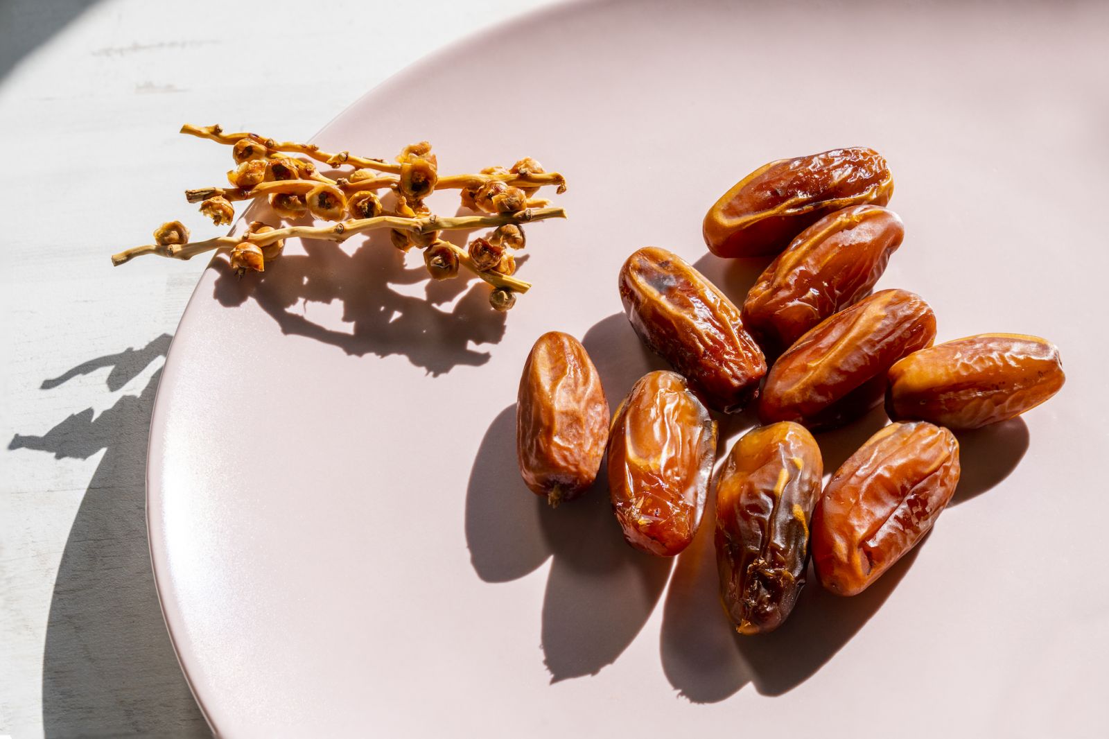 Elevated view of some date fruits on a pink plate