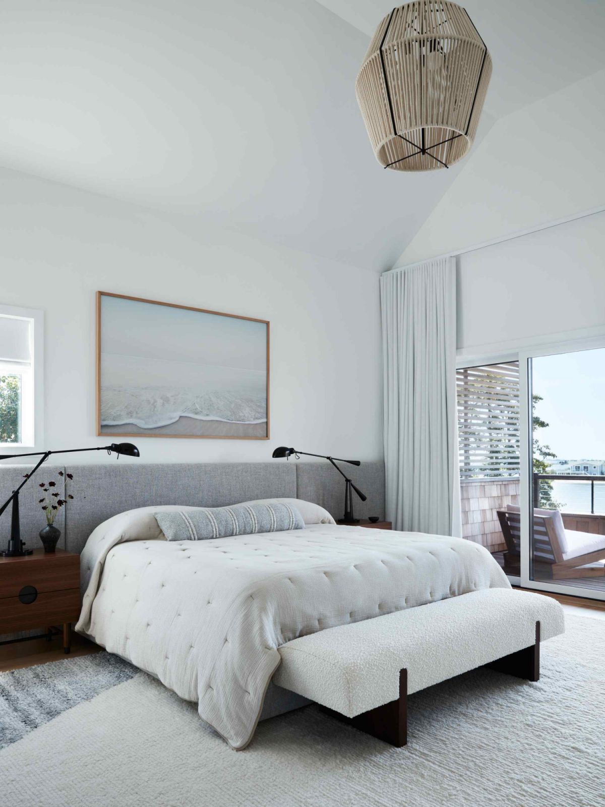 The tranquil primary bedroom with a view out to the water