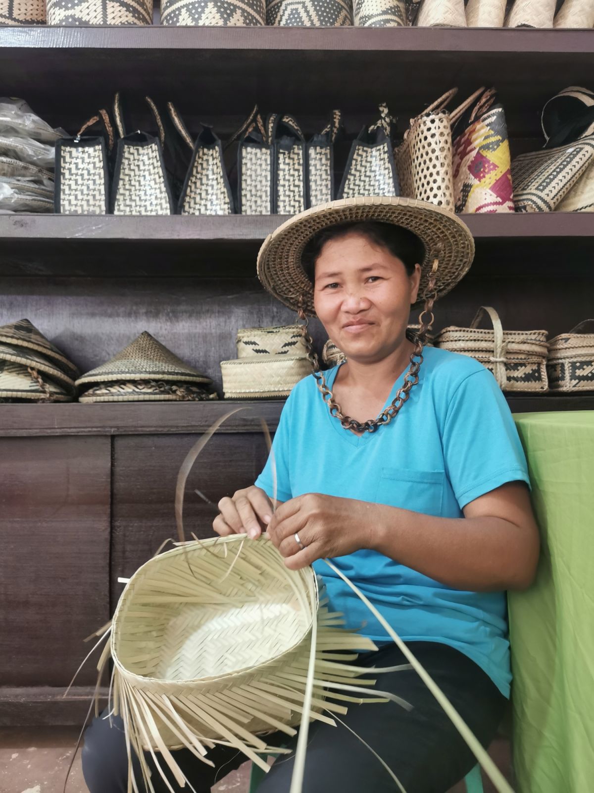 One of the weavers of South Upi Monom Organization (SUMO) finishing her products. On display behind her are other SUMO products displayed in their Weaving and Display Centre (Photo: Accelerate H)