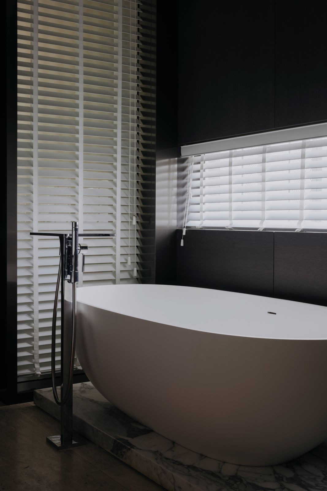 The bathtub’s elliptical shape creates a striking contrast in the quadrilateral bathroom