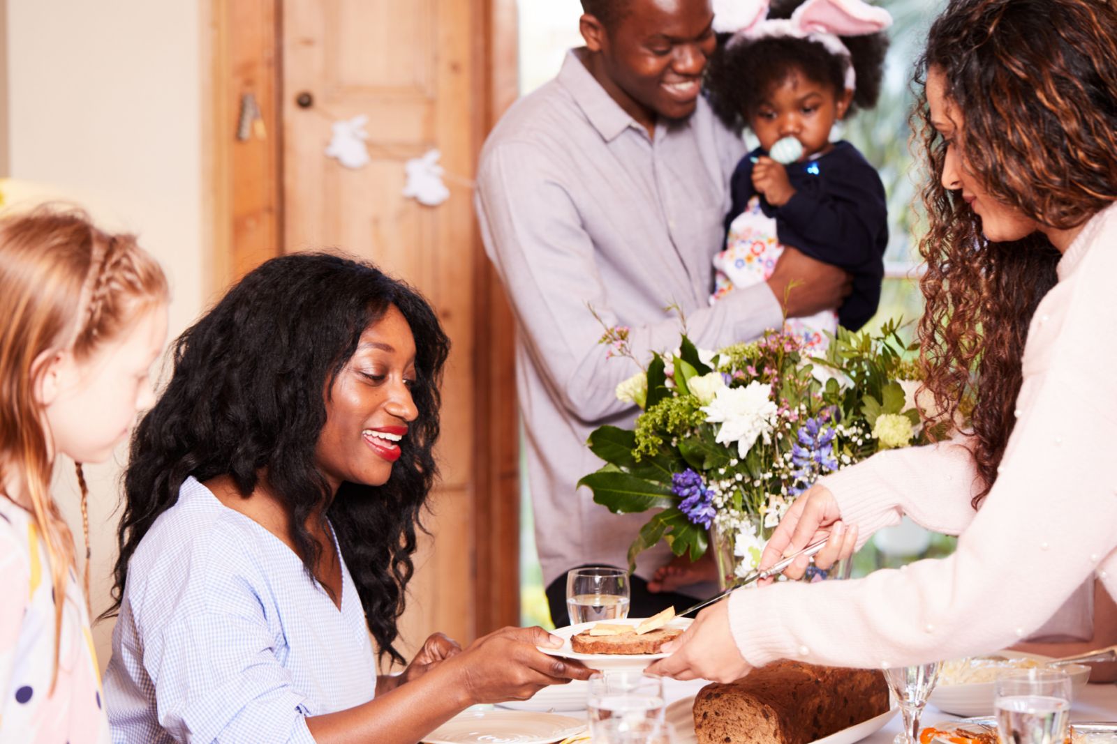 Family and friends eating their easter meal. They are eating bun and cheese, fried fish and hard dough bread all of which are a Caribbean Easter Tradition.