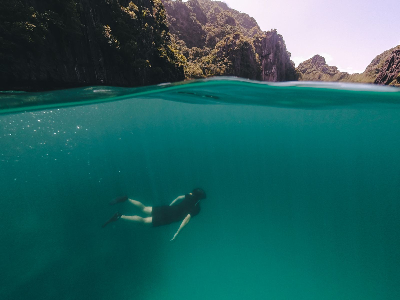 Slit photo of man swimming underwater and big rock formations above water in El Nido Palawan, Philippines (Photo: Gabriel Mello/Getty Images)