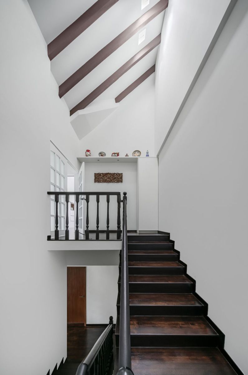 The white walls and dark wood staircase and roof structure create a striking view