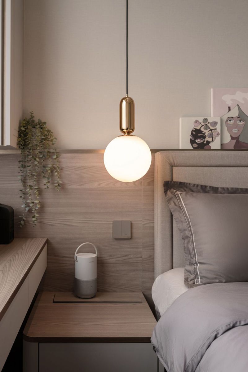 Artwork displayed above the headboard and a low-hanging pendant lamp are among the interesting touches in this bedroom