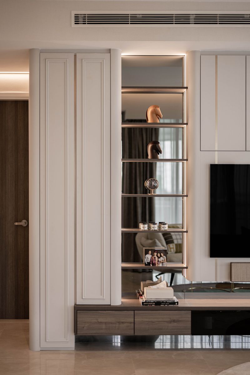 A backlit and mirrored shelving unit displays curios and a family portrait photo