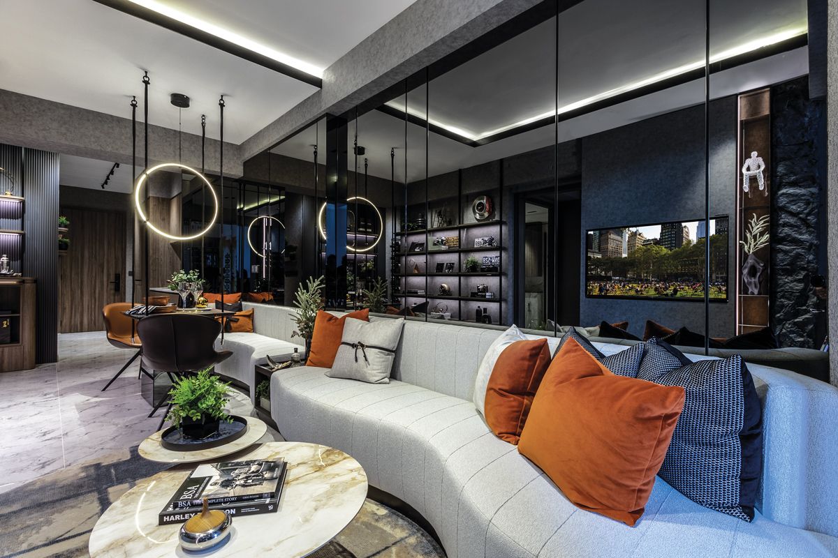 Mirrored wall panels expand the sense of space in this two-bedroom unit, while a pair of custom sofas in curvaceous forms lines the length of the open-plan living and dining room