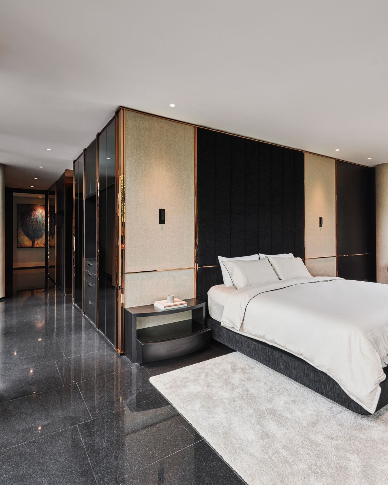 The headboard in the master suite does double duty as a wall of the adjoining walk-in wardrobe