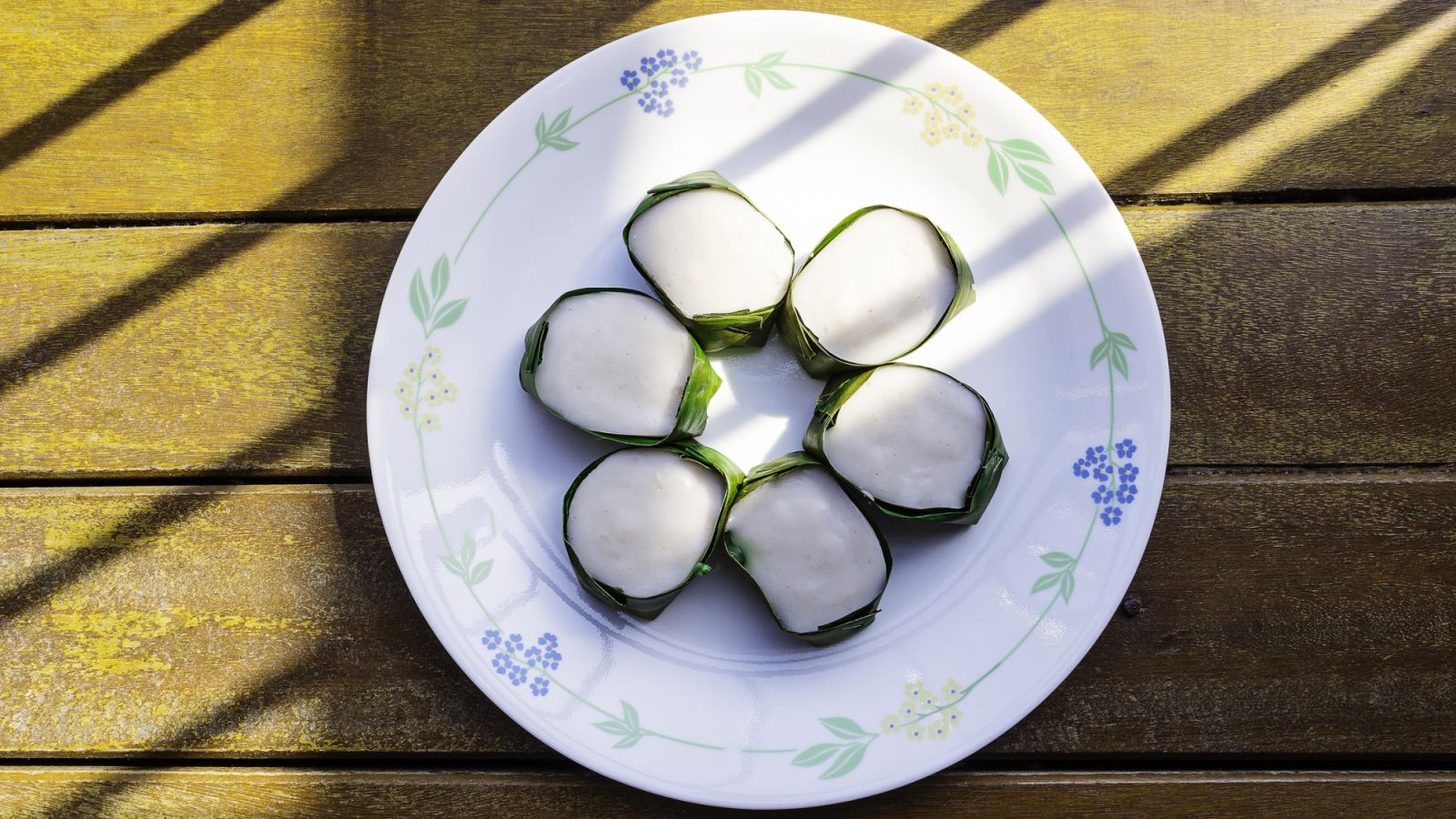 A tray of tepung pelita—layers of coconut and pandan pudding wrapped in a banana leaf (Photo: Getty Images)