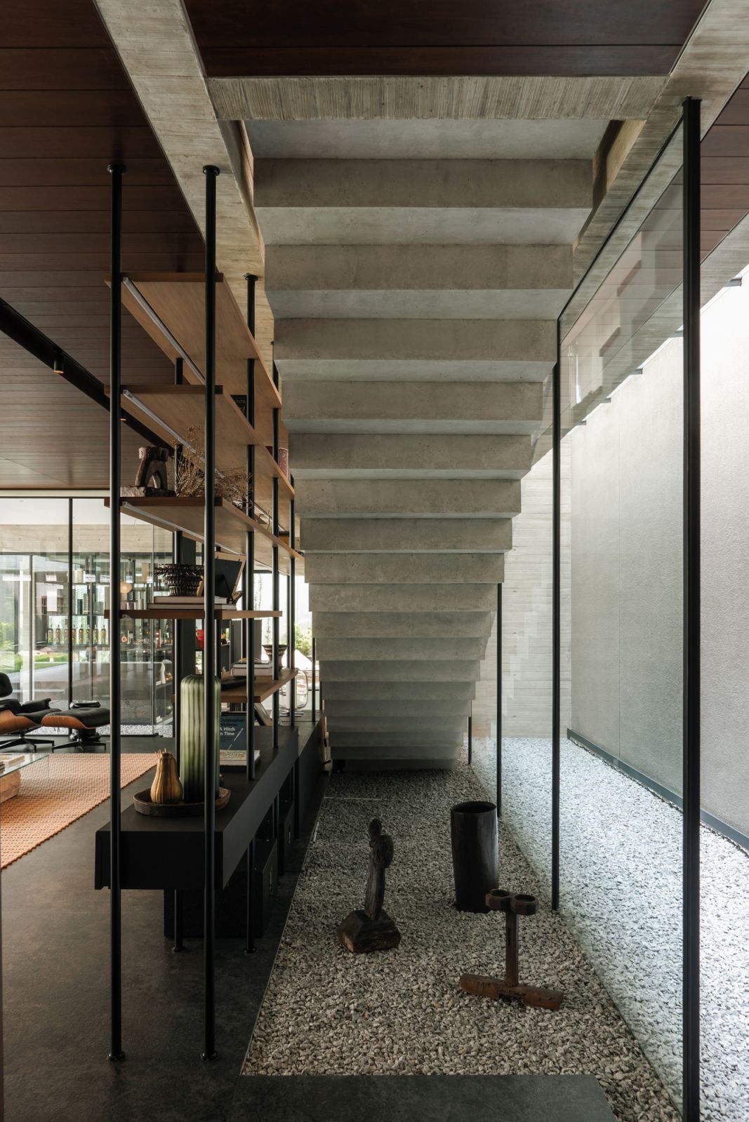 The indoor and outdoor spaces share the same material palette, as shown by the gravel bed beneath the stairs