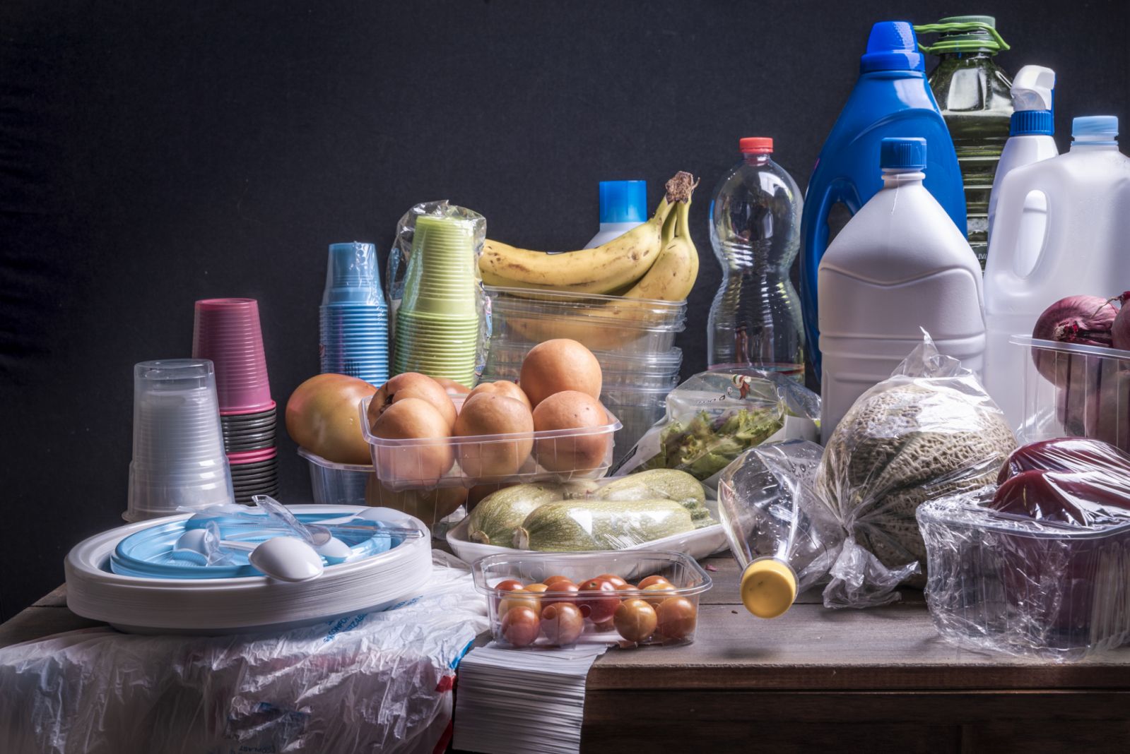 Piatti, bottiglie, bicchieri flaconi e vaschette in plastica, tutta plastica usata quotidianamente sul Tavolo fotografata con luci still life