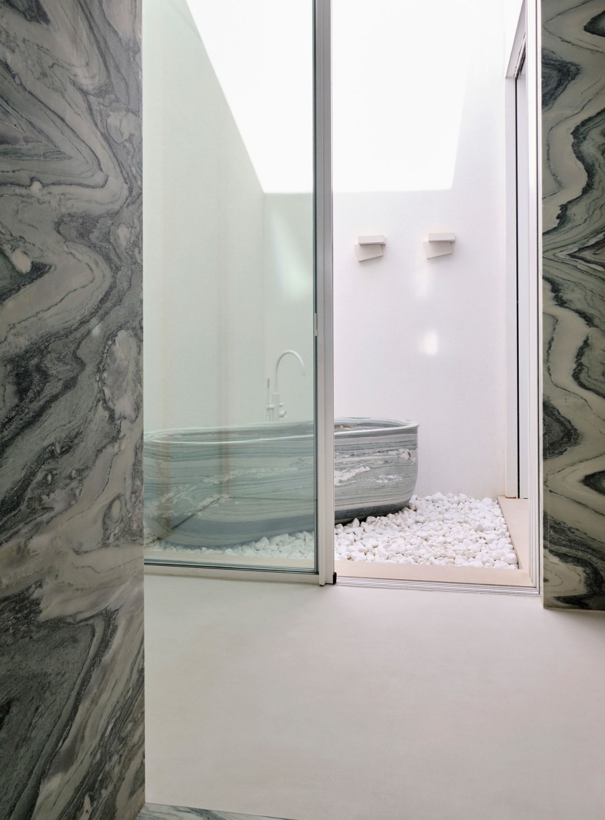 The lavish guest bathroom features dramatic Cipollino marble slabs and sleek fittings from Vola