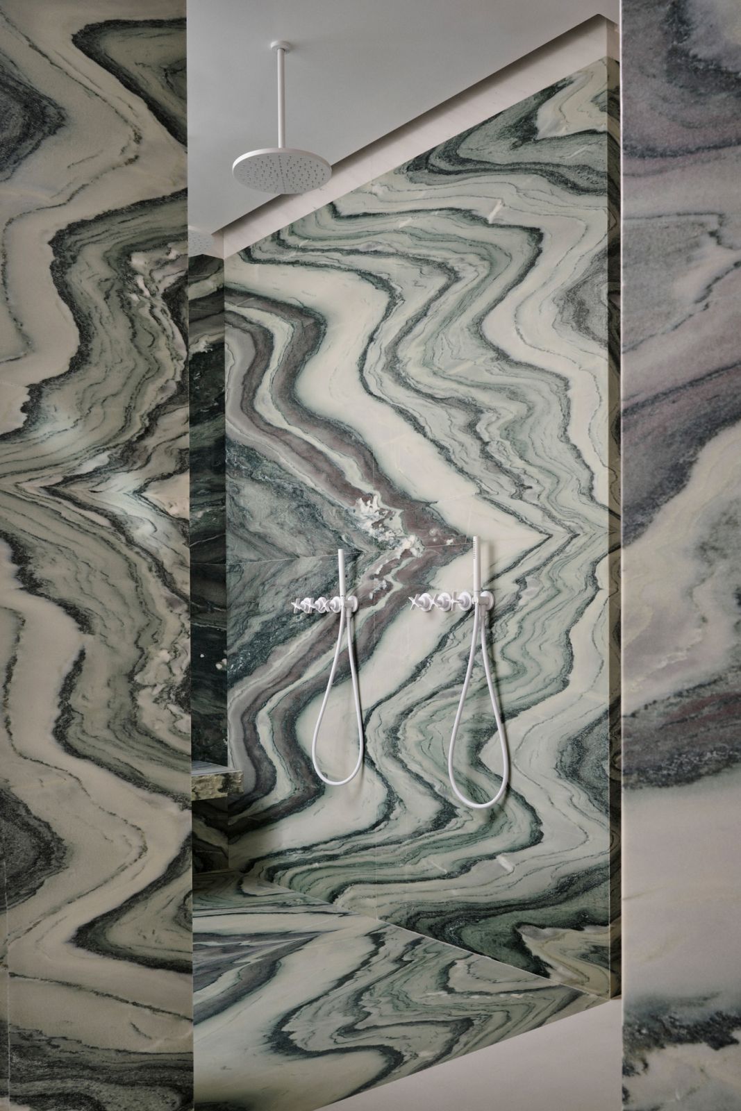The lavish guest bathroom features dramatic Cipollino marble slabs and sleek fittings from Vola