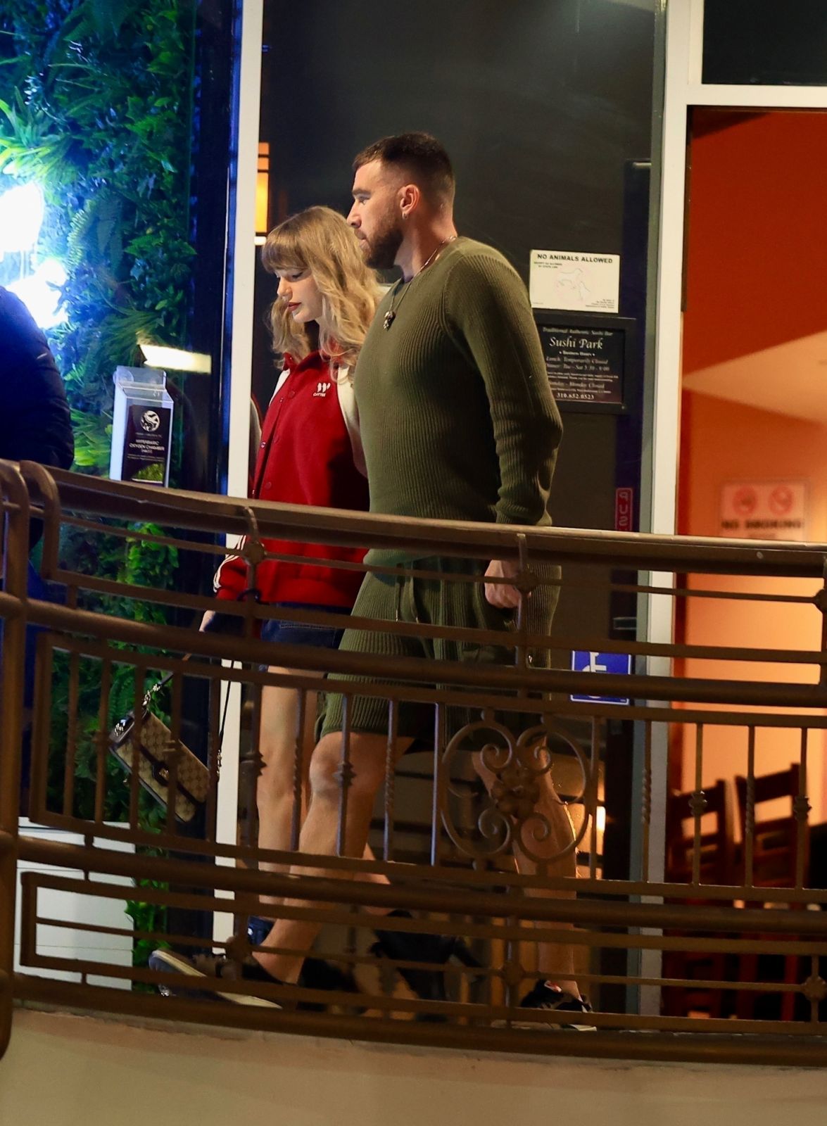 Los Angeles, CA  - *PREMIUM-EXCLUSIVE*  - Taylor Swift gracefully departs Sushi Park in LA alongside her beau, Travis Kelce, their affection palpable in every tender gesture and shared gaze, a captivating glimpse into their enchanting romance. Taylor was all smiles as the two made their way into the hot spot restaurant. Taylor wore her favorite color, a red jacket while Travis rocked a monochrome green knit set. The couple was rumored to be attending Coachella together in support of her bff Lana Del Rey, bu