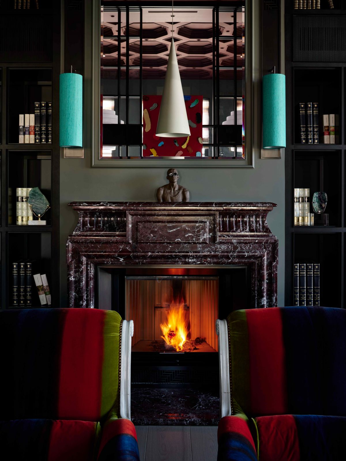 The opulent marble fireplace between the floor-to-ceiling bookshelves