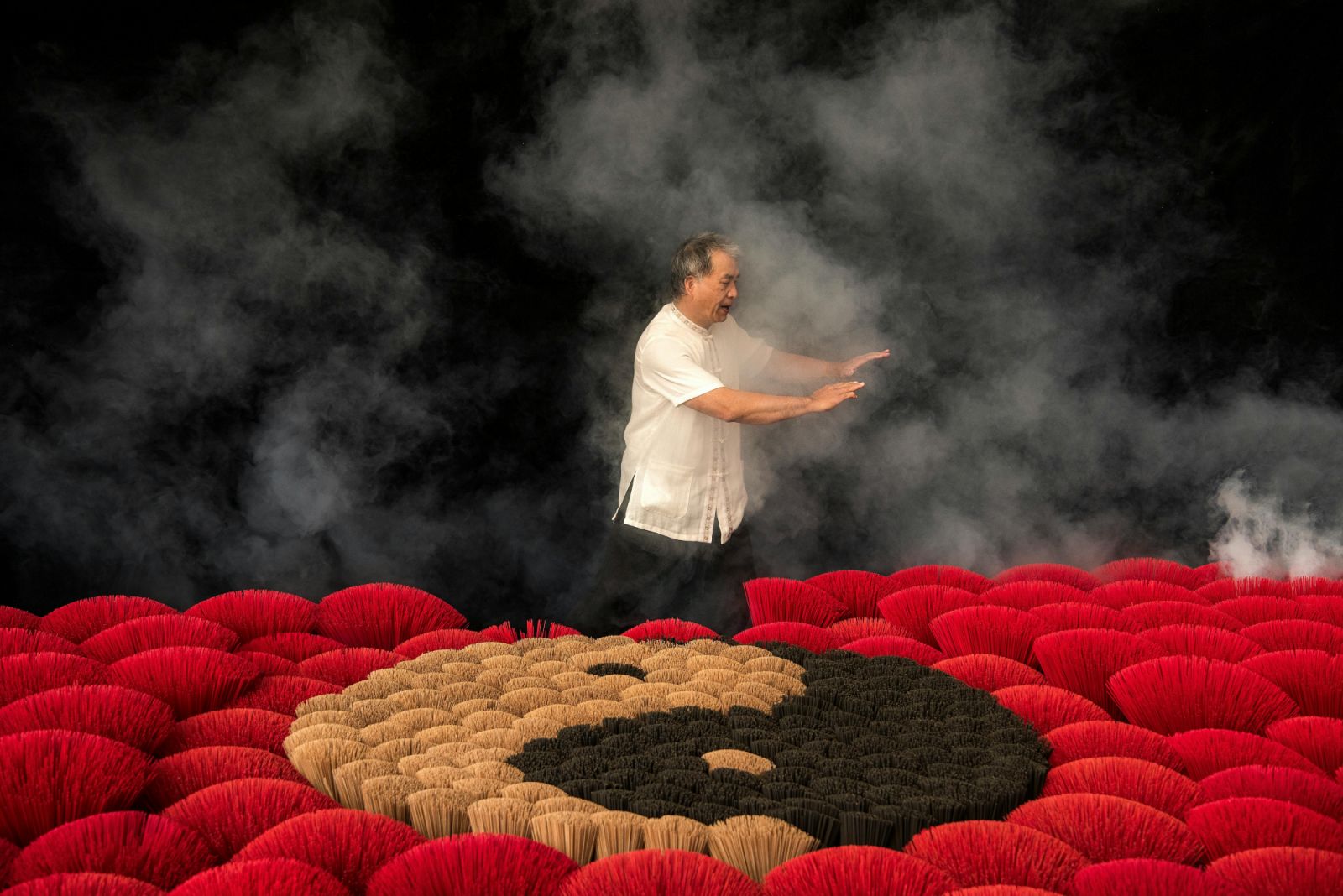 Man practicing tai chi next to incenses forming yin and yang symbol (Photo: Klub Boks / Pexels)