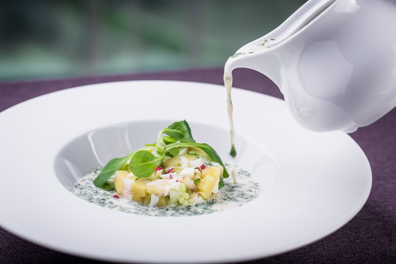 Russian national cold soup okroshka a sour milk drink is poured into the plate