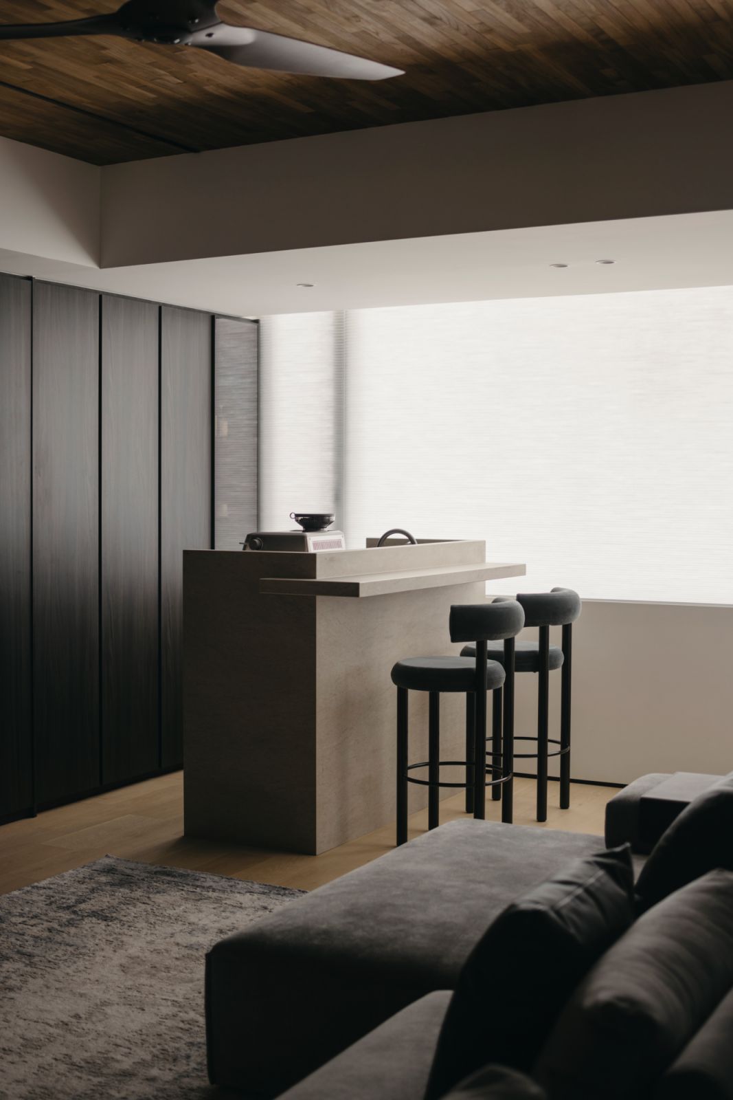 The living room’s timber flooring is mirrored by the wooden ceiling, enveloping the space with texture and warmth