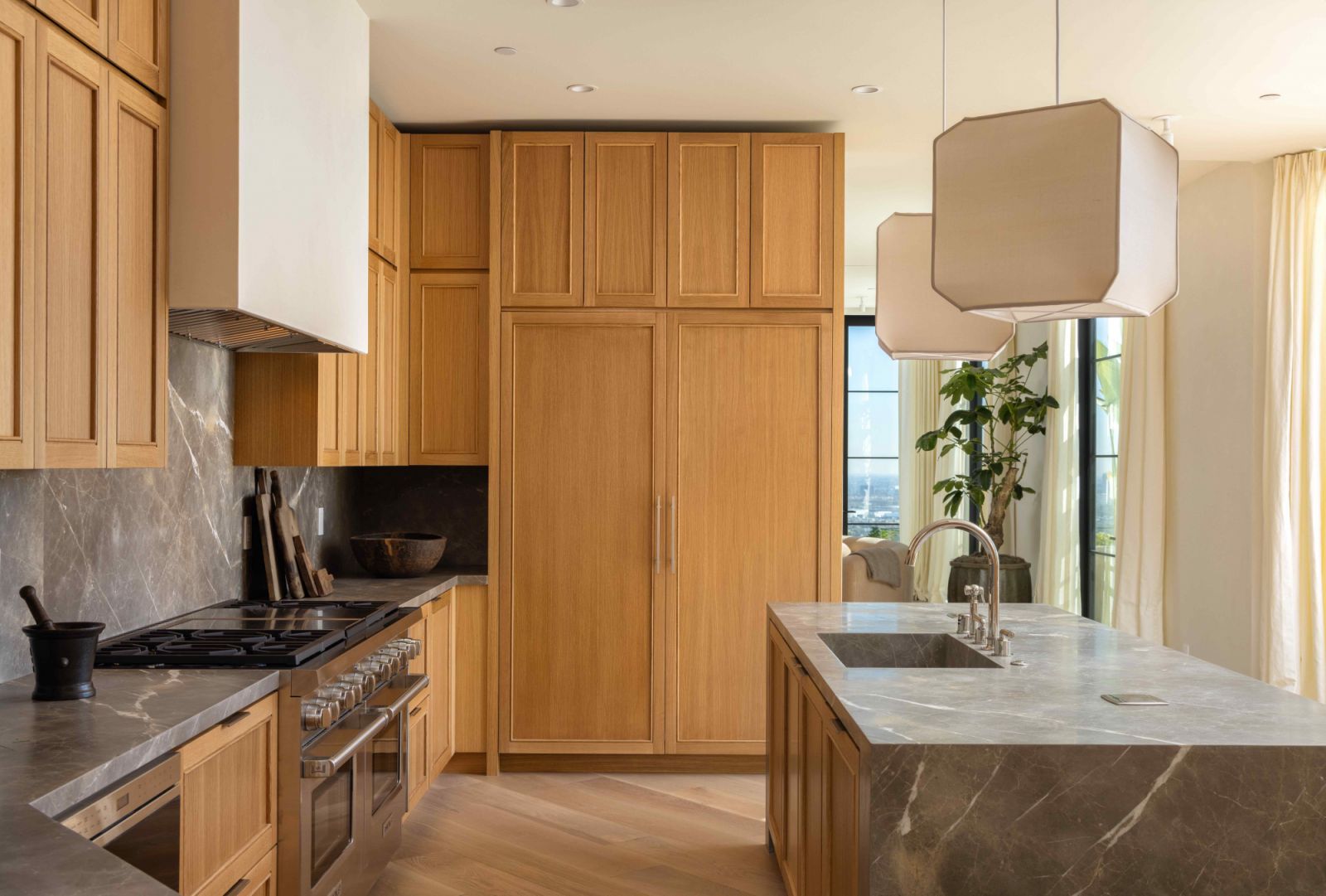 Light oak wood cabinetry and flooring and supple light fixtures add warmth and cosiness