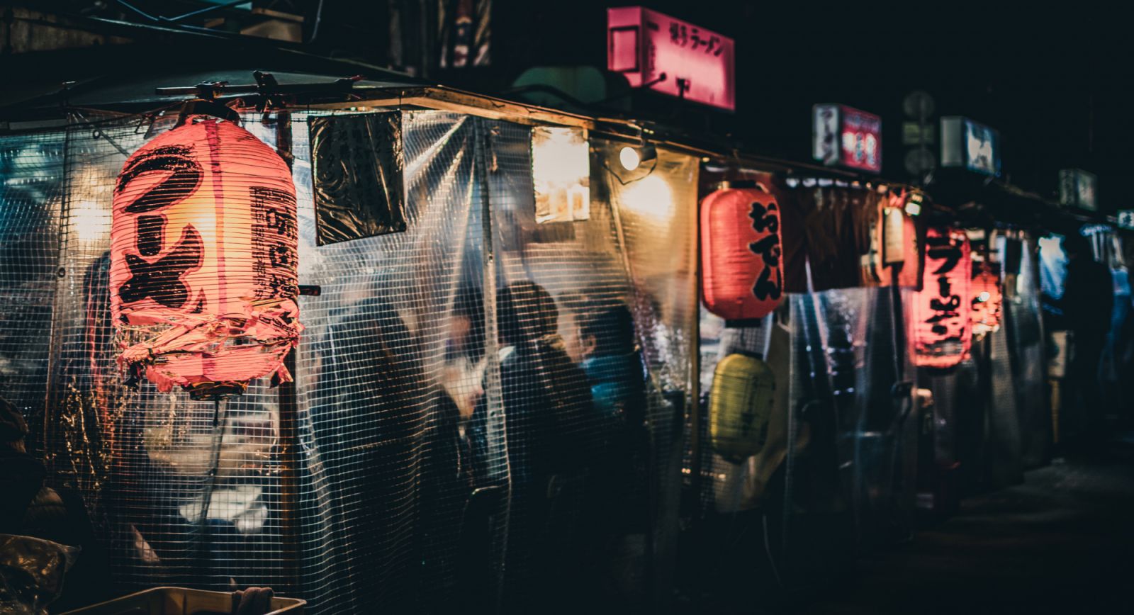 Japanese street food sold out of "yatai" food stalls in Fukuoka (Hakata), Japan. Signs say "ramen," "oden," "Hakata ramen" with no business names visible.