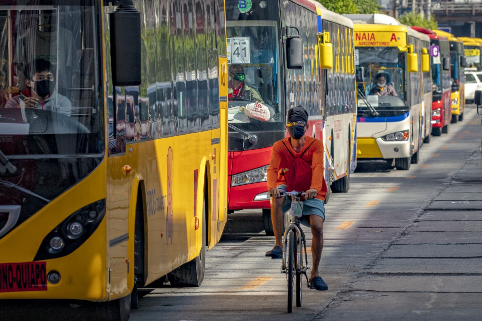 A cyclist rides past a queue of buses on the first day of relaxed quarantine measures on June 1, 2020 in Quezon city, Metro Manila (Photo by Ezra Acayan/Getty Images)