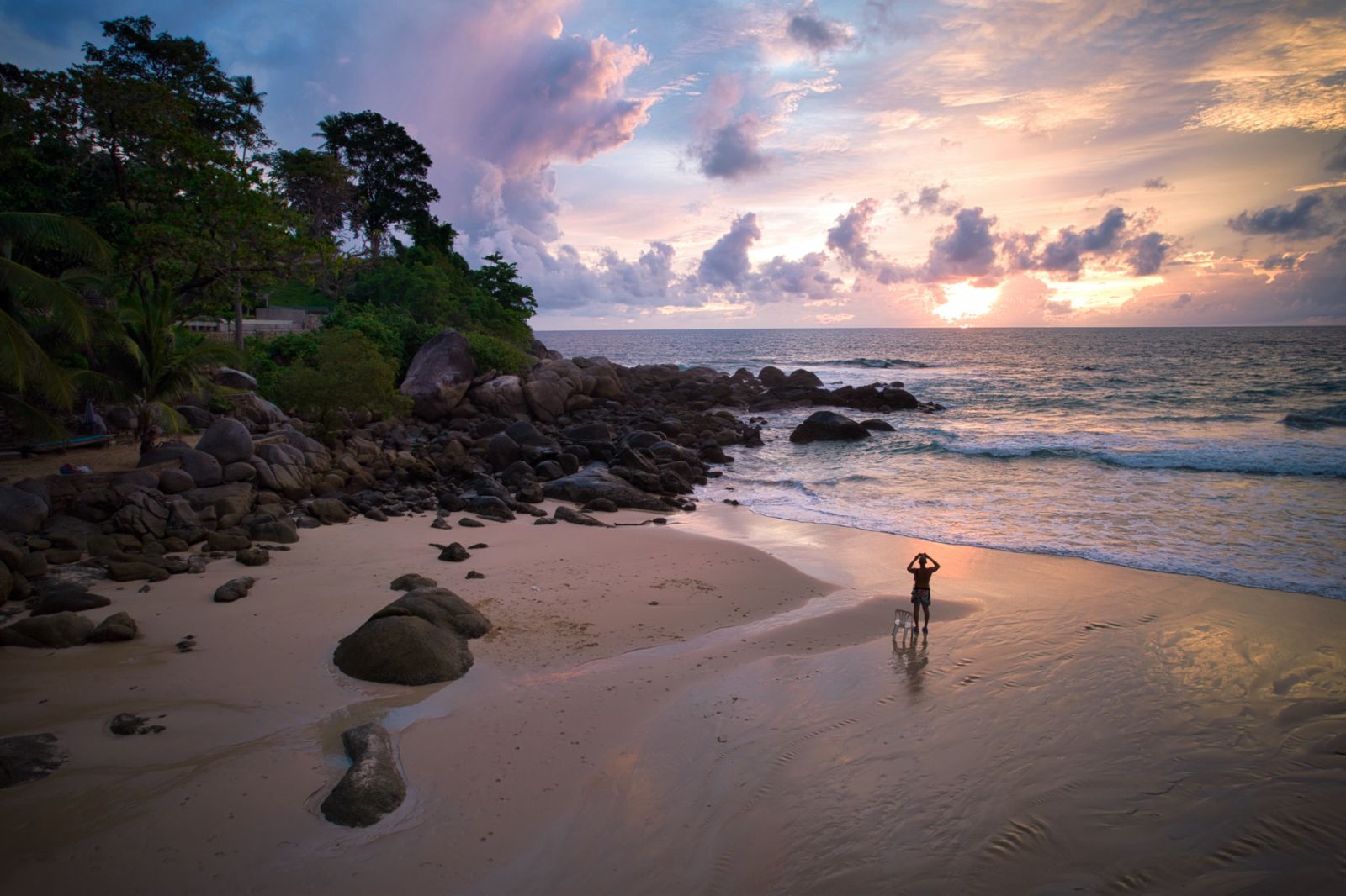 A traveller taking picture on the beautiful rock beach when sunset at Kata noi beach during Phuket sandbox program, Phuket, Thailand.