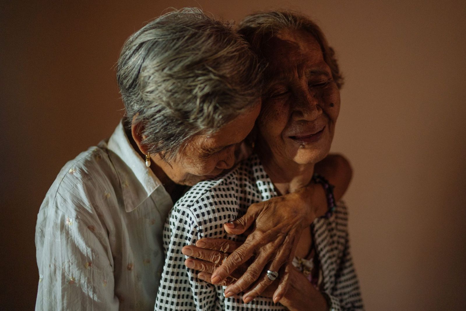 Lydia and Emilia, part of the 'Malaya Lolas' group, laugh and hug during a portrait session in Pampanga, Philippines. The group of survivors of mass rape all live near each other in the area where they were kept captive (Photo: Hannah Reyes Morales)