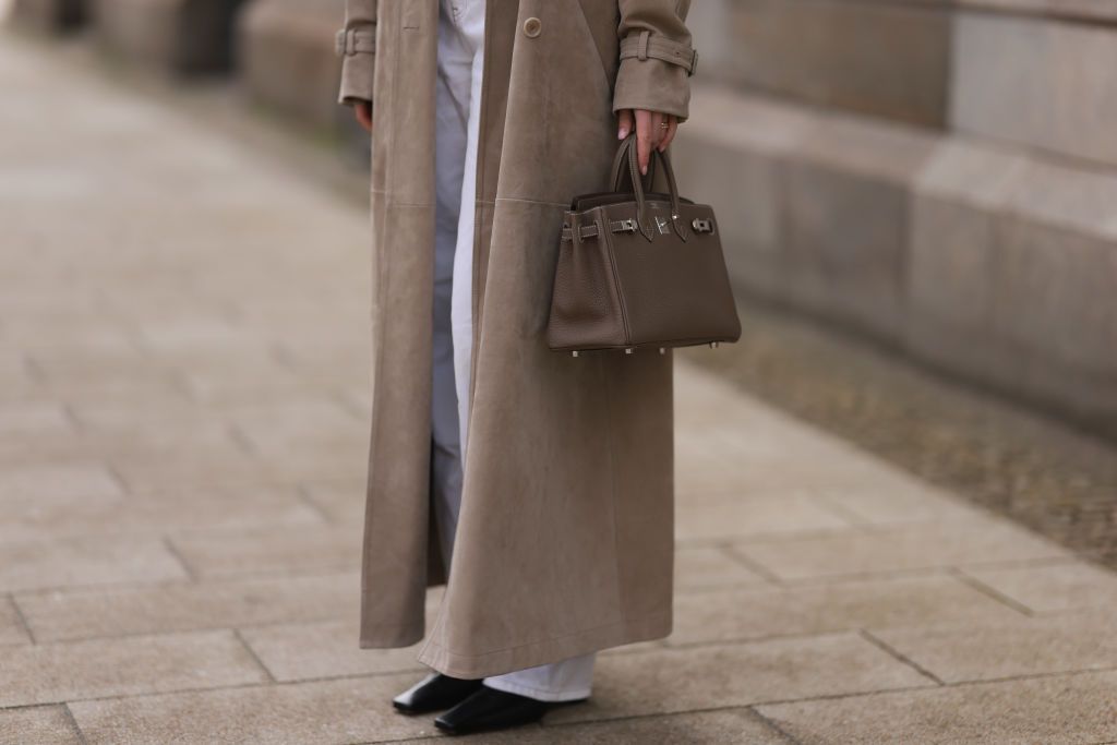 HAMBURG, GERMANY - APRIL 05: Isabelle Hartmann seen wearing COS white cotton basic t-shirt, Max Mara beige suede leather oversized trenchcoat / long coat, Leviâs white vintage denim straight leg jeans, HermÃ¨s Birkin 25 brown / taupe leather handbag and Khaite black leather boots on April 05, 2024 in Hamburg, Germany.  (Photo by Jeremy Moeller/Getty Images)