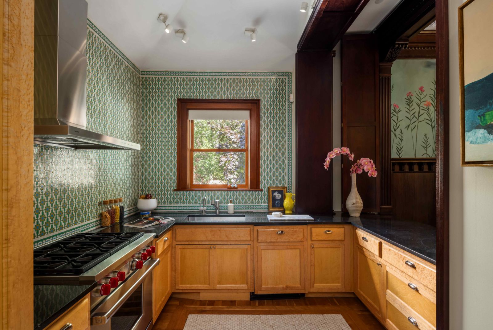 The verdant palette persists in the kitchen's patterned tile walls