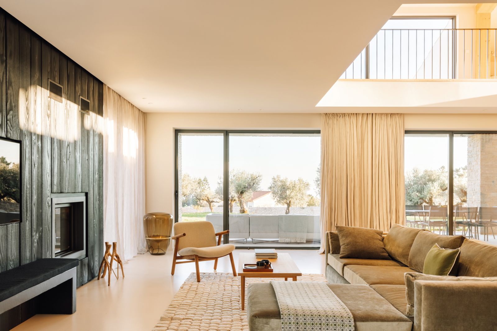 The living area is organised around the fireplace, which was designed with burnt wood planks that also act as a backdrop for the TV