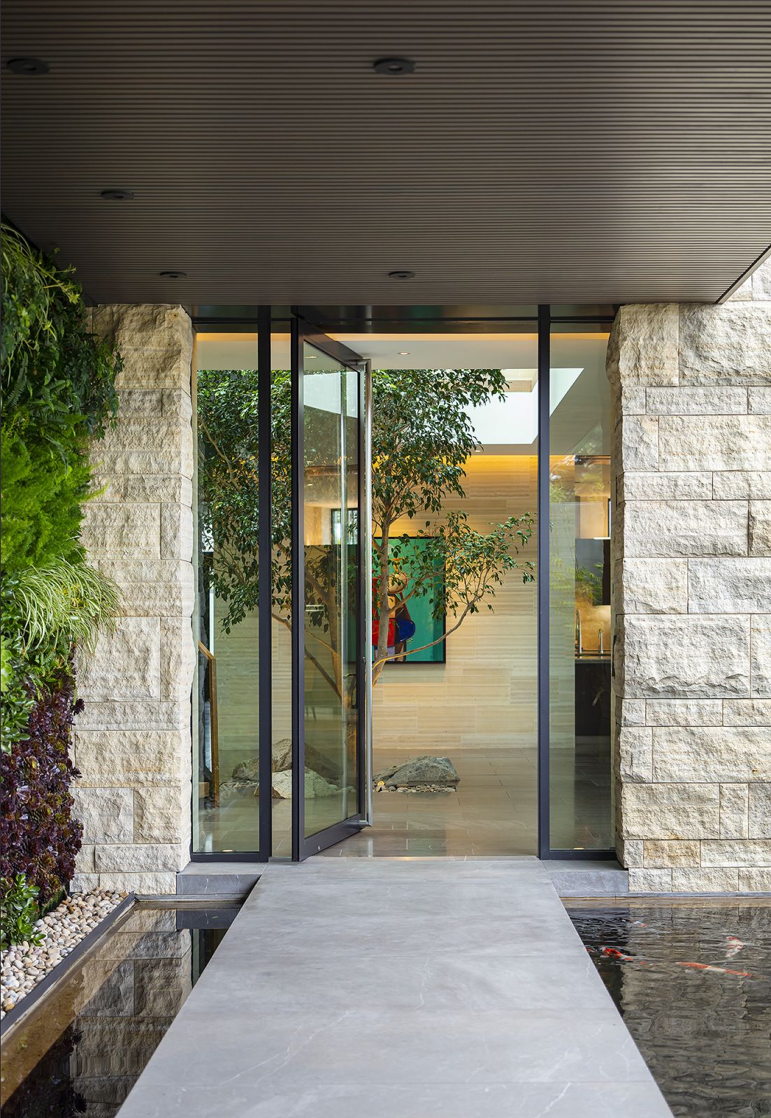 The cantilevered glass door leads to the biophilic foyer