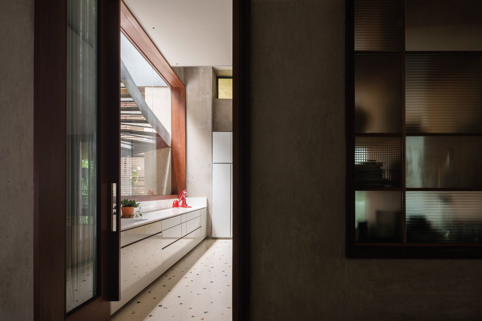The kitchen’s material palette combines terrazzo and textured glass with wood and concrete