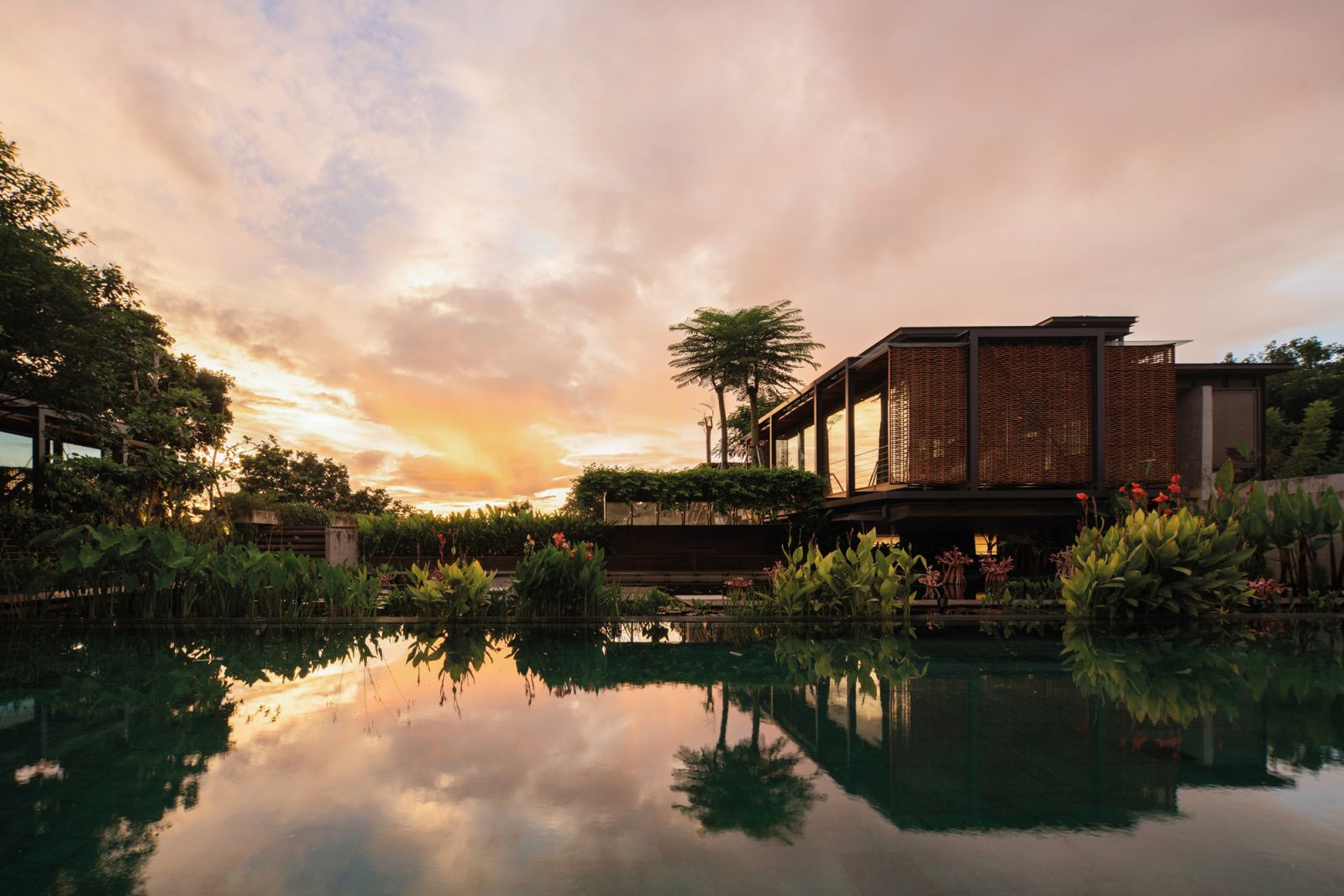 A stunning sunset vista of the house and its aquascaped pond, which is the highest level of the seven-tiered pools and water filtration system