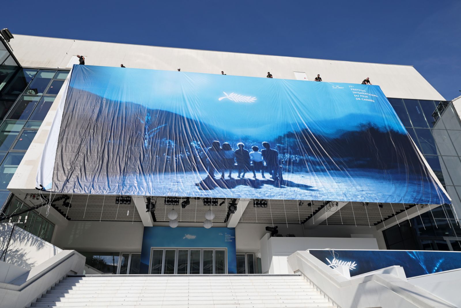 CANNES, FRANCE - MAY 12: Workers install the official poster on the Palais de Festival ahead of the 77th annual Cannes Film Festival at on May 12, 2024 in Cannes, France. (Photo by Pascal Le Segretain/Getty Images)