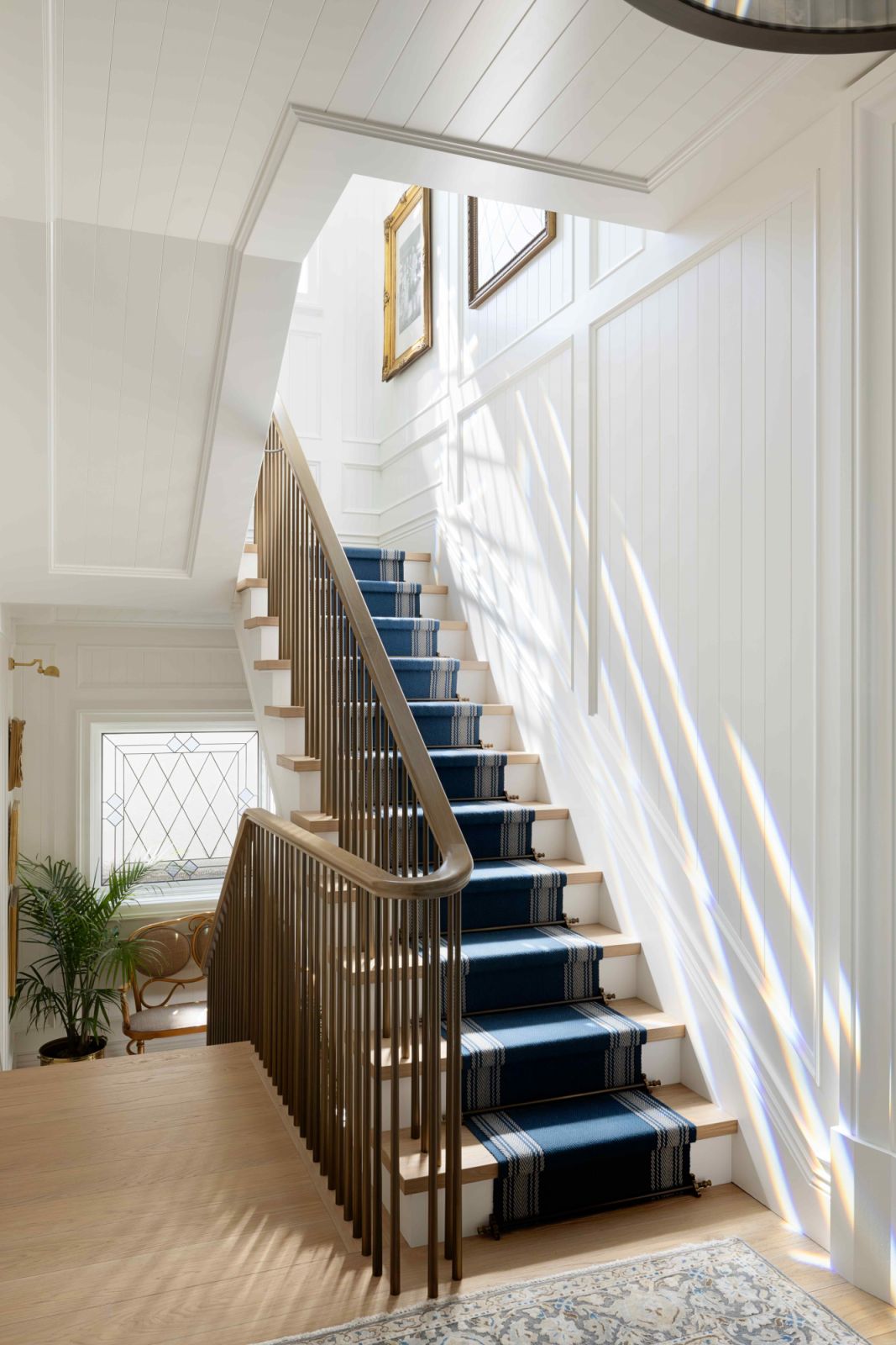 Raised panels and ship lap upon crisp and white walls up the stairwell