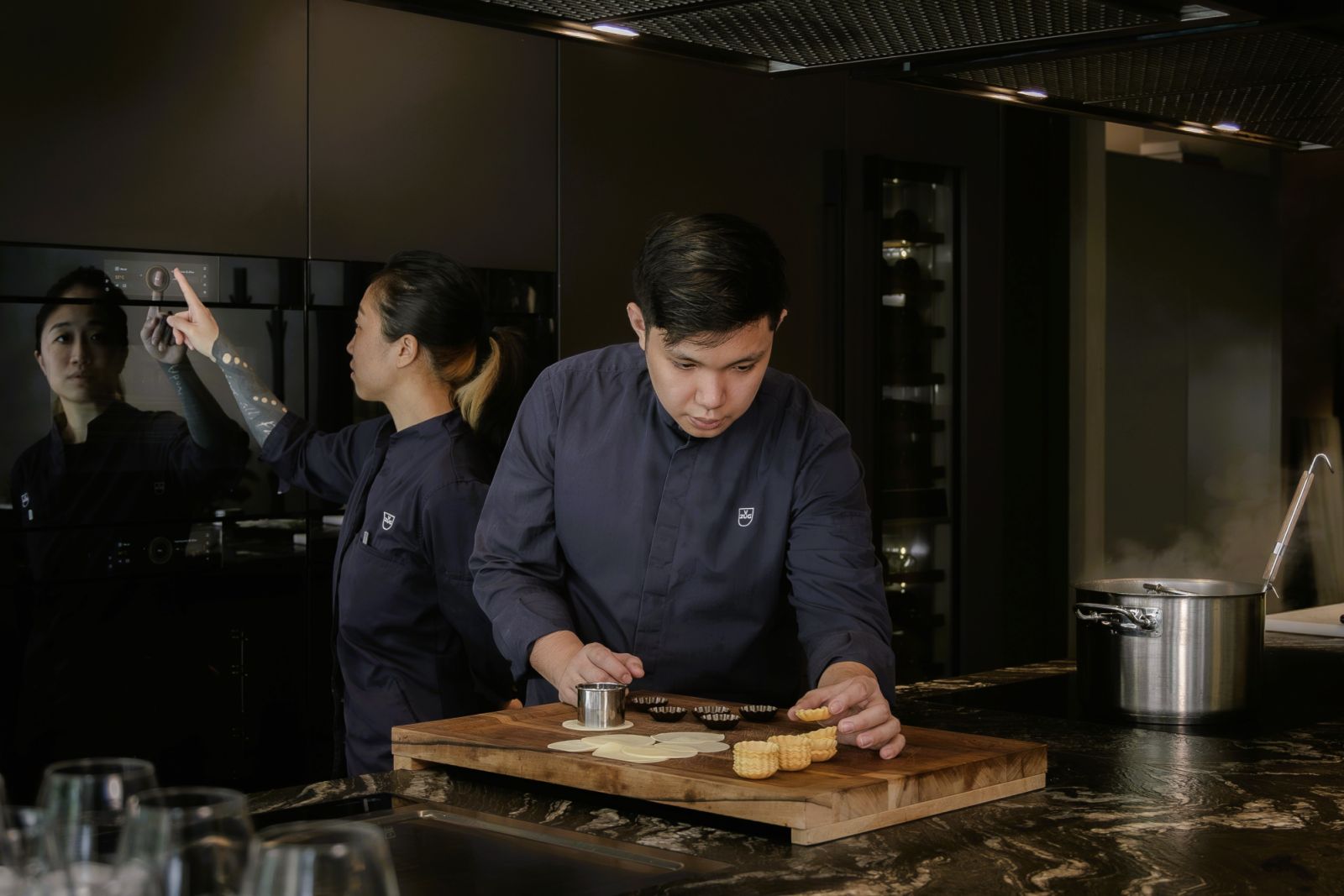 Chefs Ow and Ng doing preparatory work for a dish