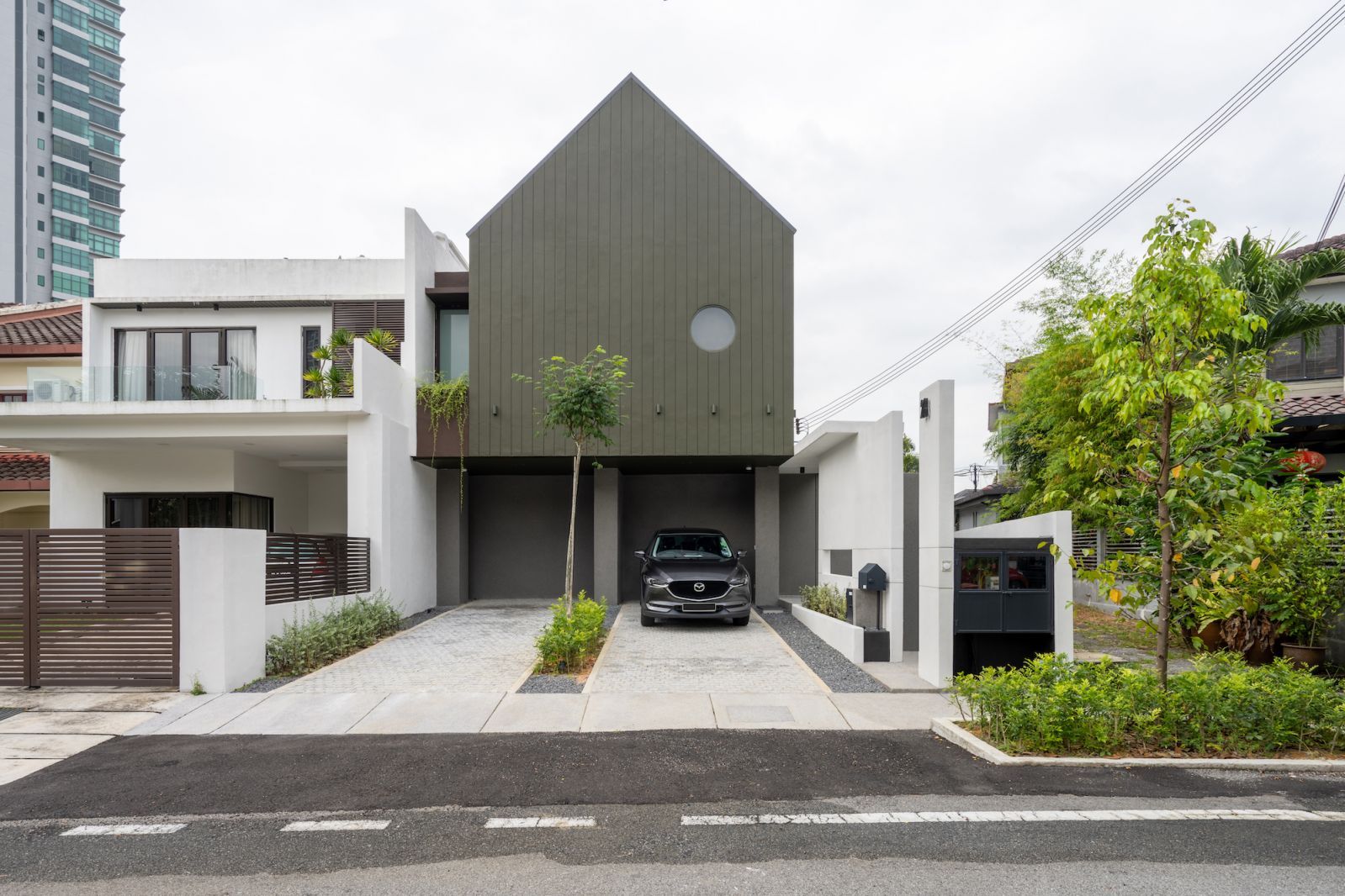 The prominent dark green pitched roof façade (Photo: BricksBegin)