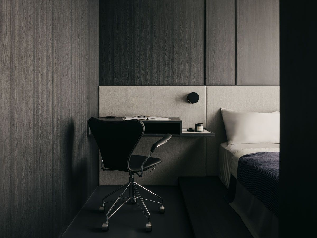 The custom headboard incorporates a desk and bedside table for spatial efficiency