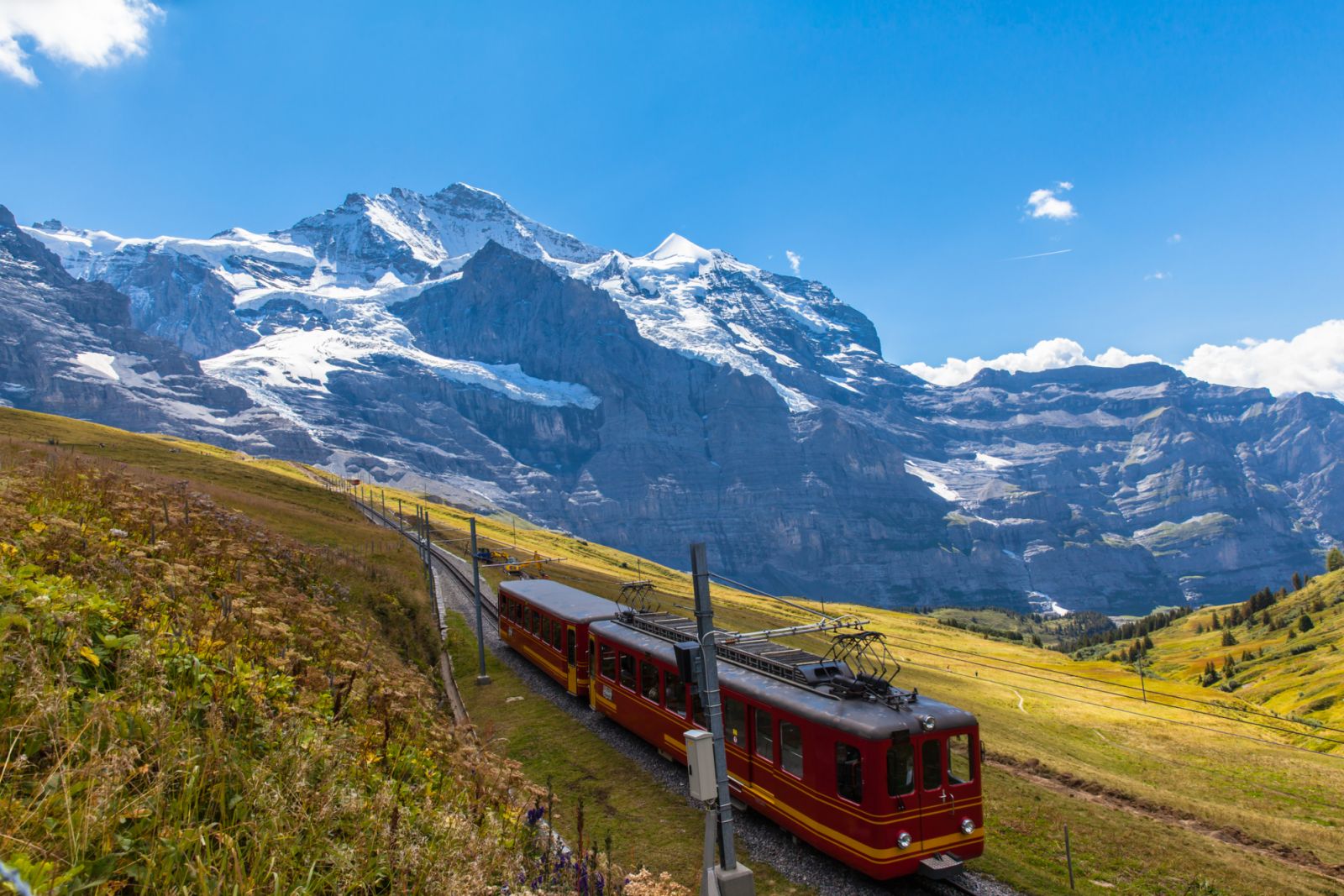 Train of Jungfraubahn running towards Jungfraujoch under the famous peak Jungfrau near the station Eigergletscher on bernese Oberland, Switzerland.