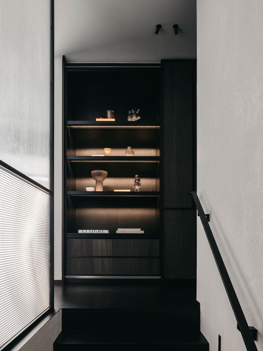 Backlit shelves populated with books and decorative items catch the eye at this staircase landing