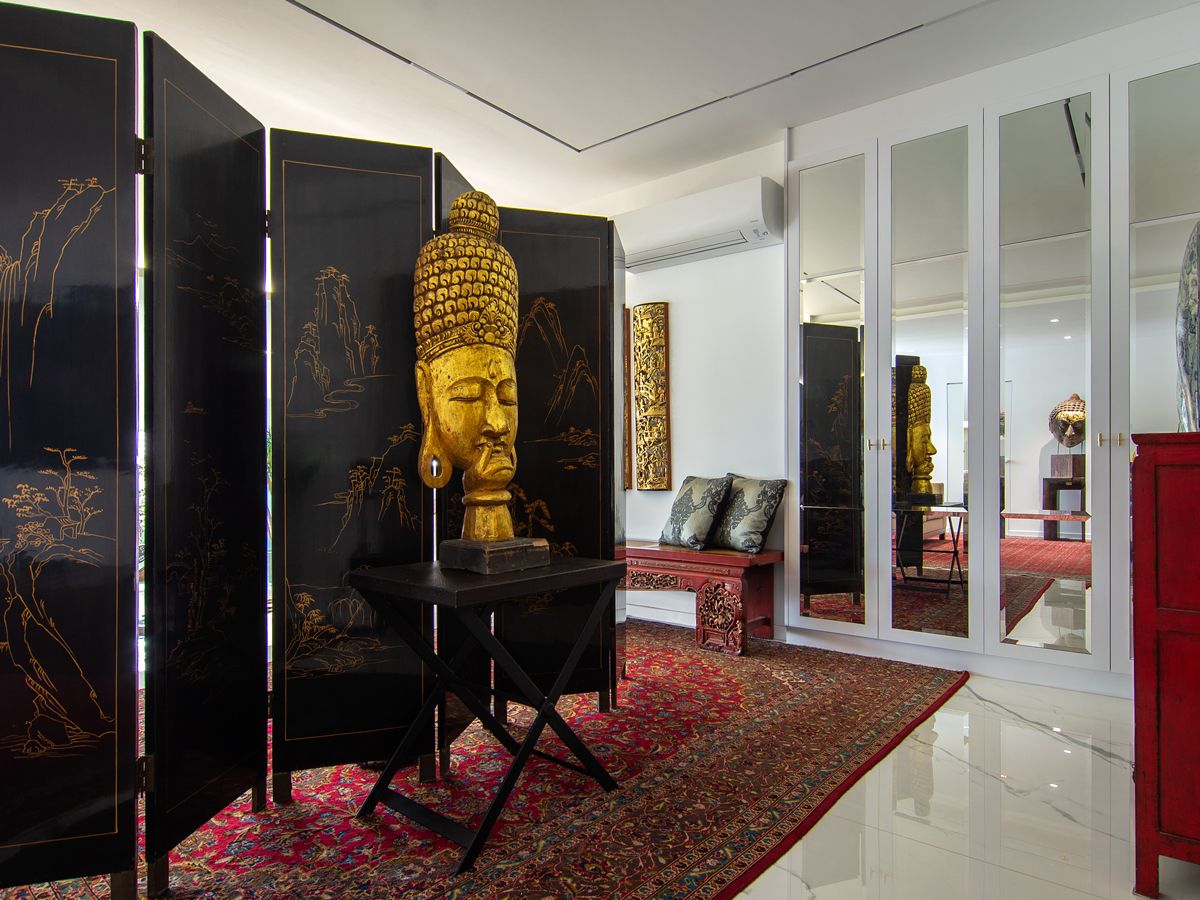 An ornamental folding screen serves as an elegant backdrop for a bust while a Turkish rug brightens the media room
